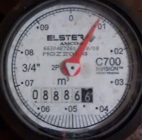 Analog water meter showing 8886.6 reading.