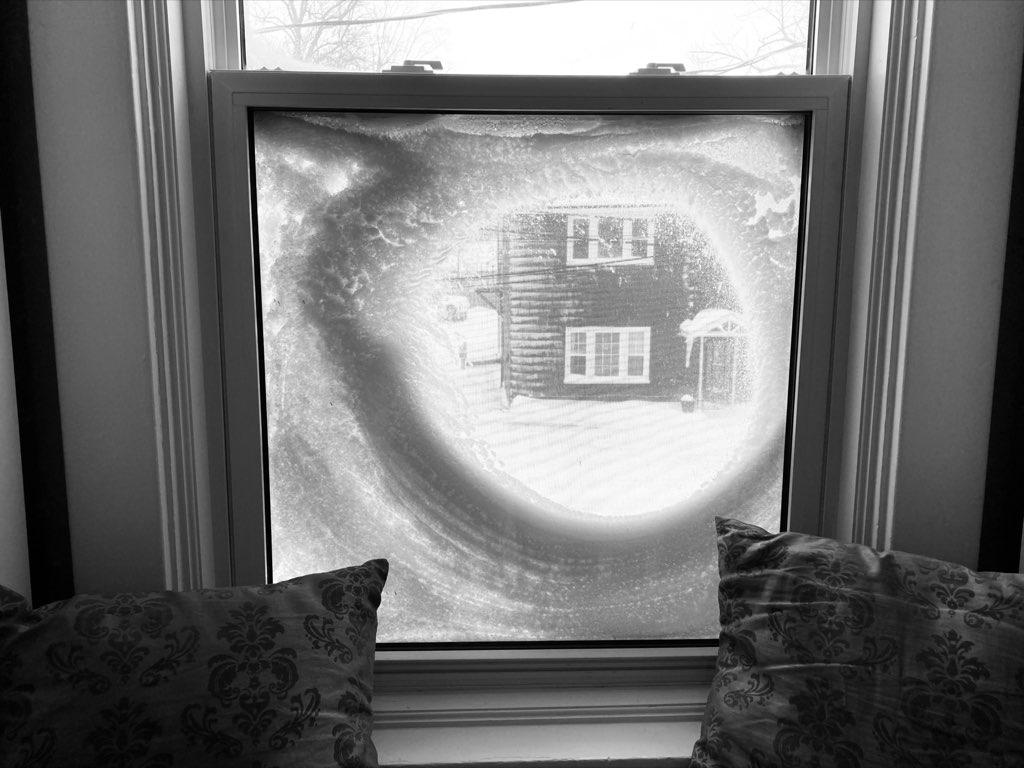 A photo of the window here at my brother's apartment, looking outside through an almost-perfect circle of snow.