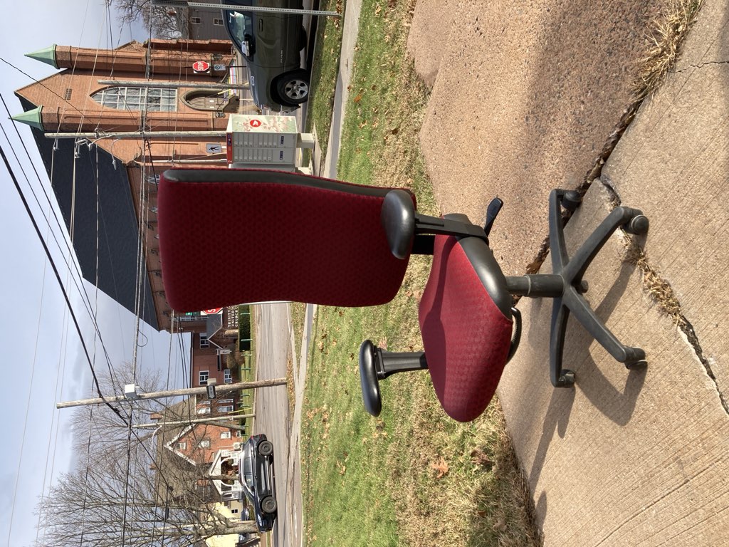 A photo of my red desk chair, on the way to the curb, sitting on the steps outside my office, on a sunny winter day.