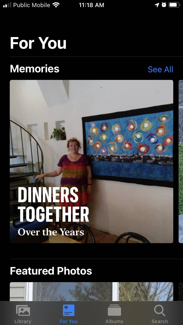 Screen shot of the For You section of the Photos app on my iPhone, showing a photo of Catherine in front of her artwork, with bold headline "Dinners Together: Over the Years" superimposed.