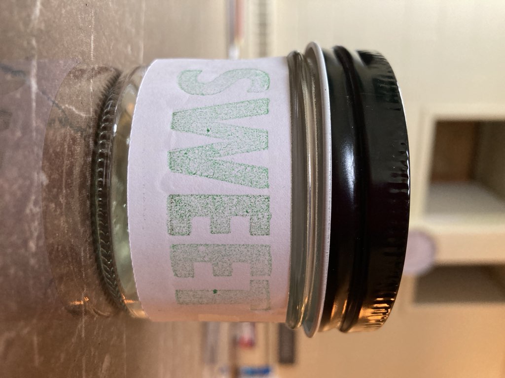 The word SWEET, in rough green type on white paper, stuck to a small jar.