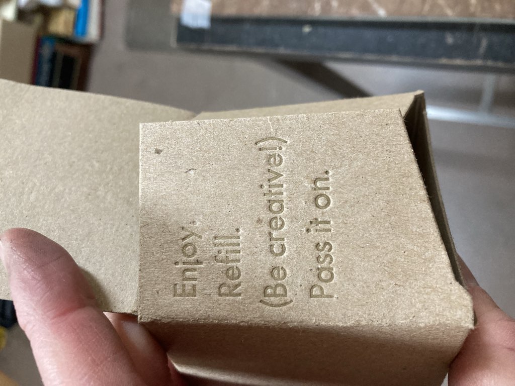 Inside flap of cardboard box printed with words "Enjoy, Refill (Be Creative), Pass It On"