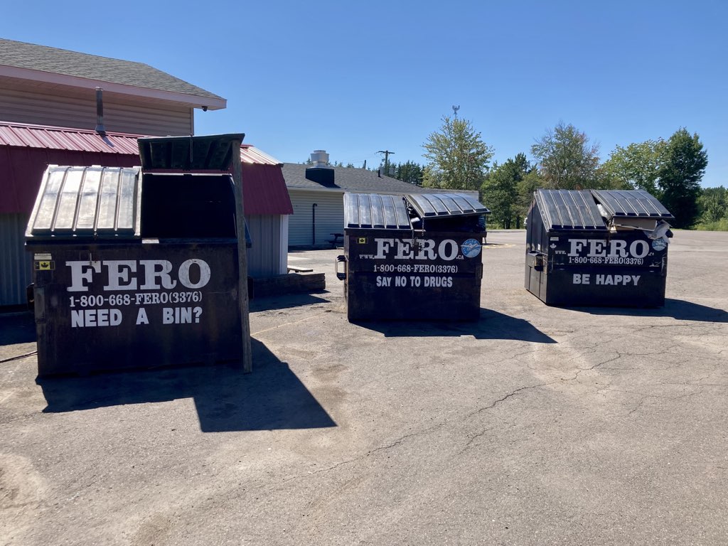 Photo of three dumpsters, each with a different slogan: Need a Bin? Say No to Drugs. Be Happy