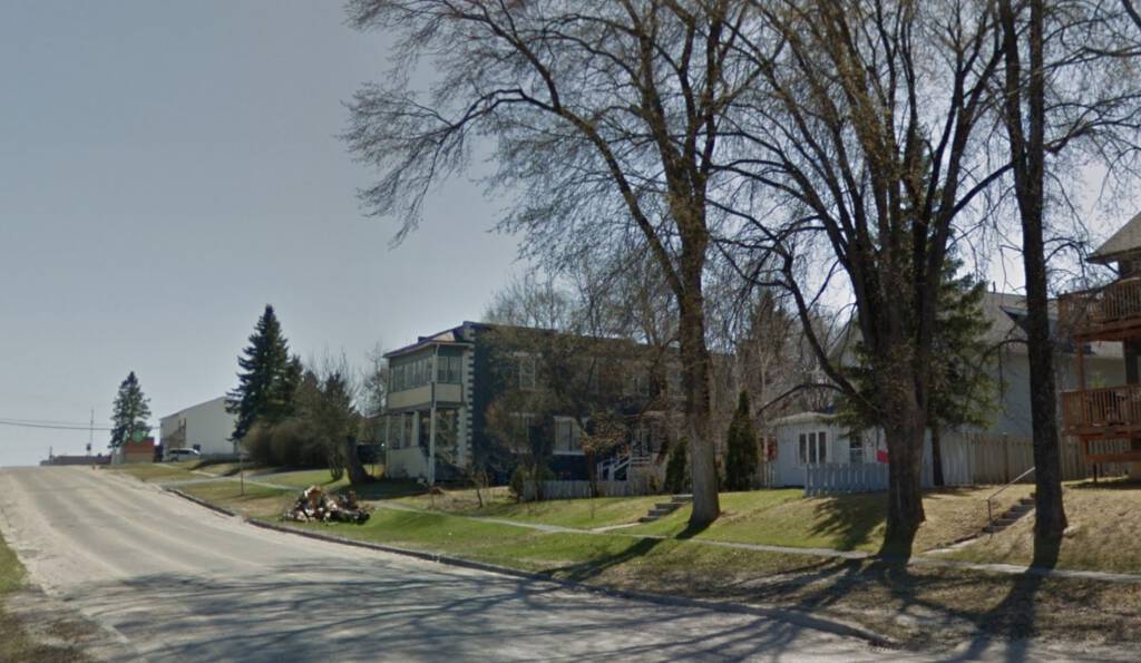 Photo from Google Street View up 5th Avenue in Cochrane, Ontario, showing a rectangular concrete-block building in the distance.