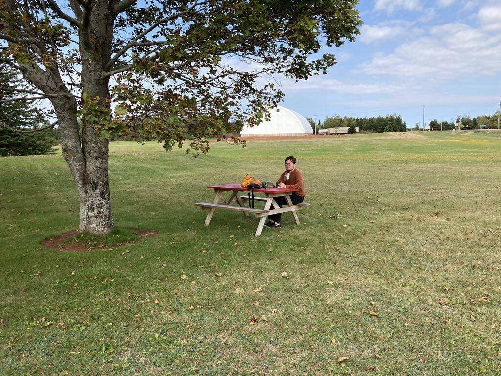 Oliver sitting at a picnic table under a tree at The Handpie Company.