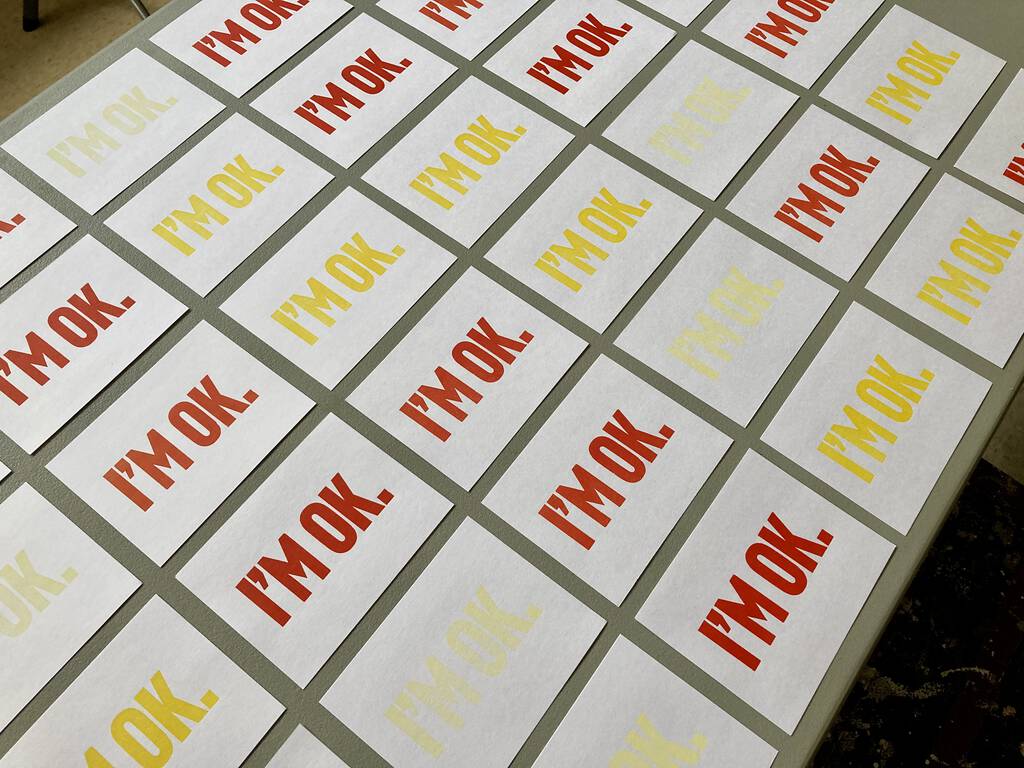 A set of "I'm OK" cards from a side view, in different colours, laid out on a table.