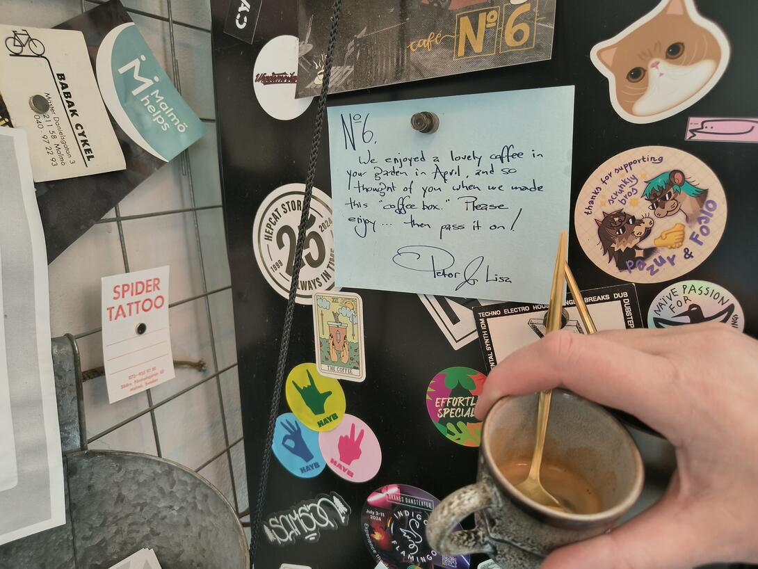 A photo of the side of a fridge in Cafe No. 6 in Malmo covered with stickers, and with a handwritten not from me and Lisa to the cafe.