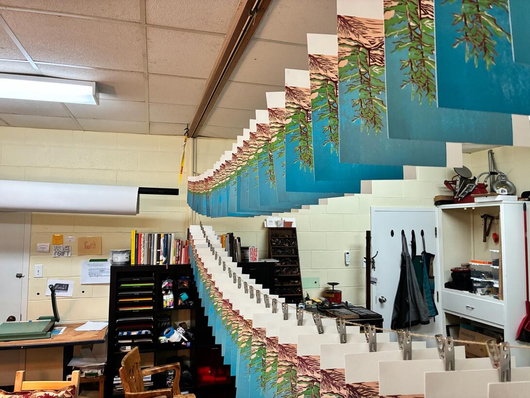 Prints hanging on a line in the print shop.
