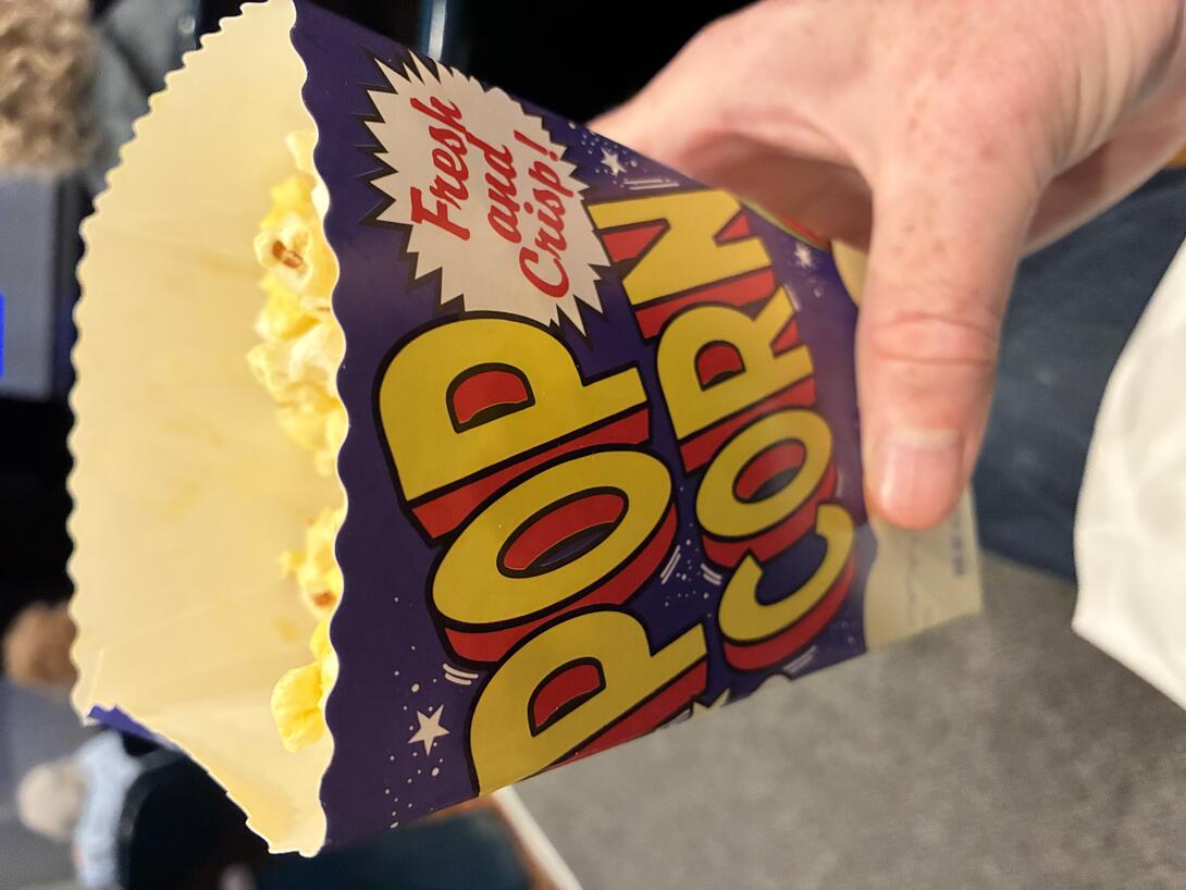 A smallish cardboard popcorn container reading "POP CORN / Fresk and Crisp!"