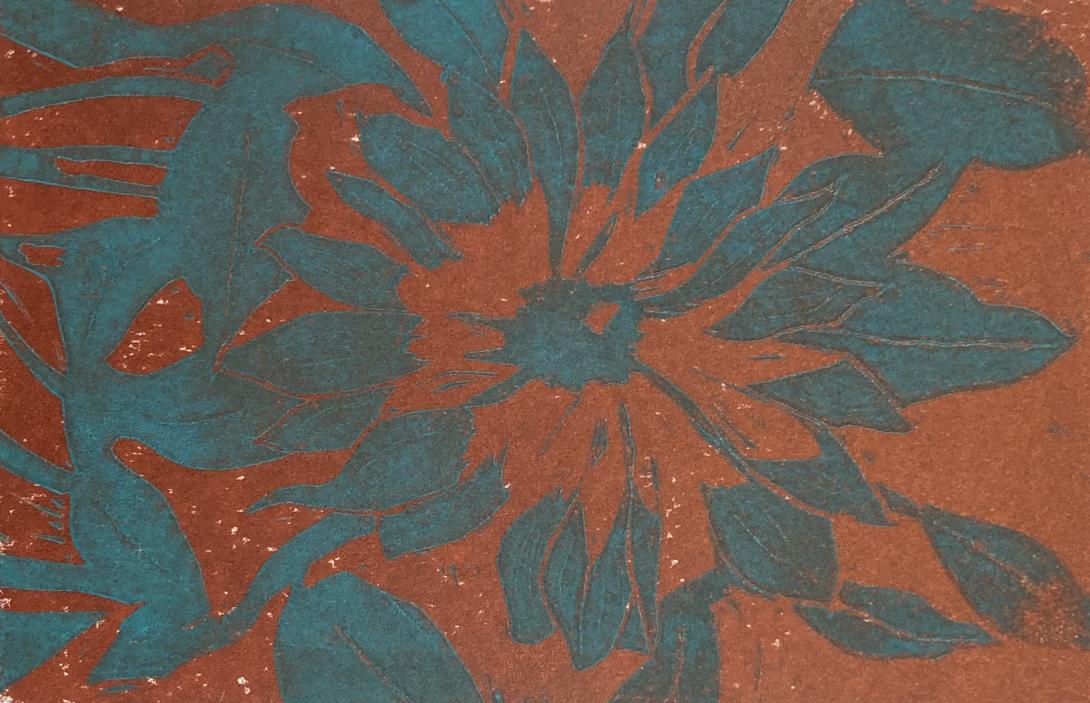 Photo of a lino block print: an abstract flower pattern printed in blue-green ink over a solid burnt sienna background.