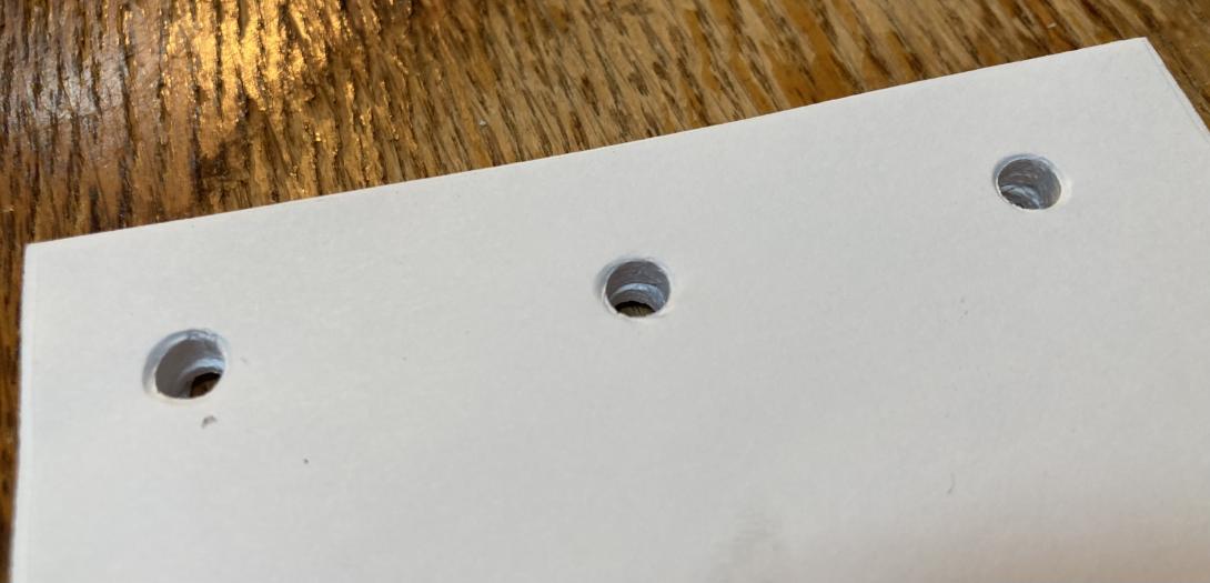 A stack of white paper with three holes drilled across the top.