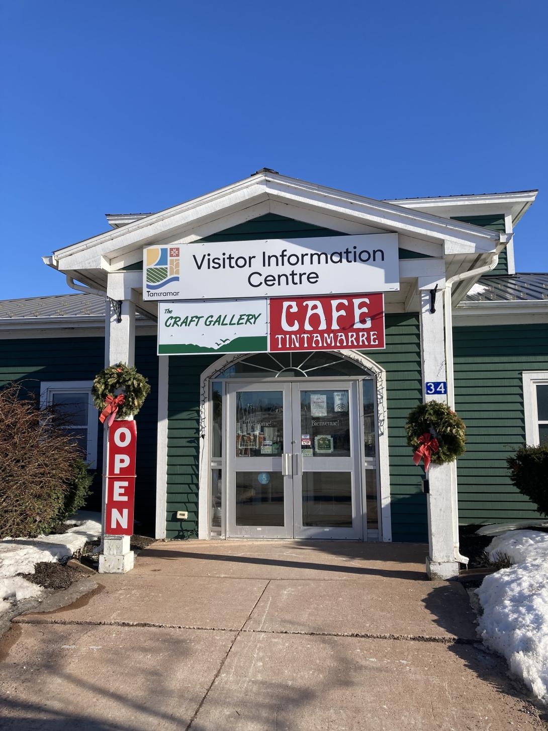 A photo of the Sackville Visitor Information Centre, with a sign over the door. There's a sign below, in red, for Cafe Tintamarre.