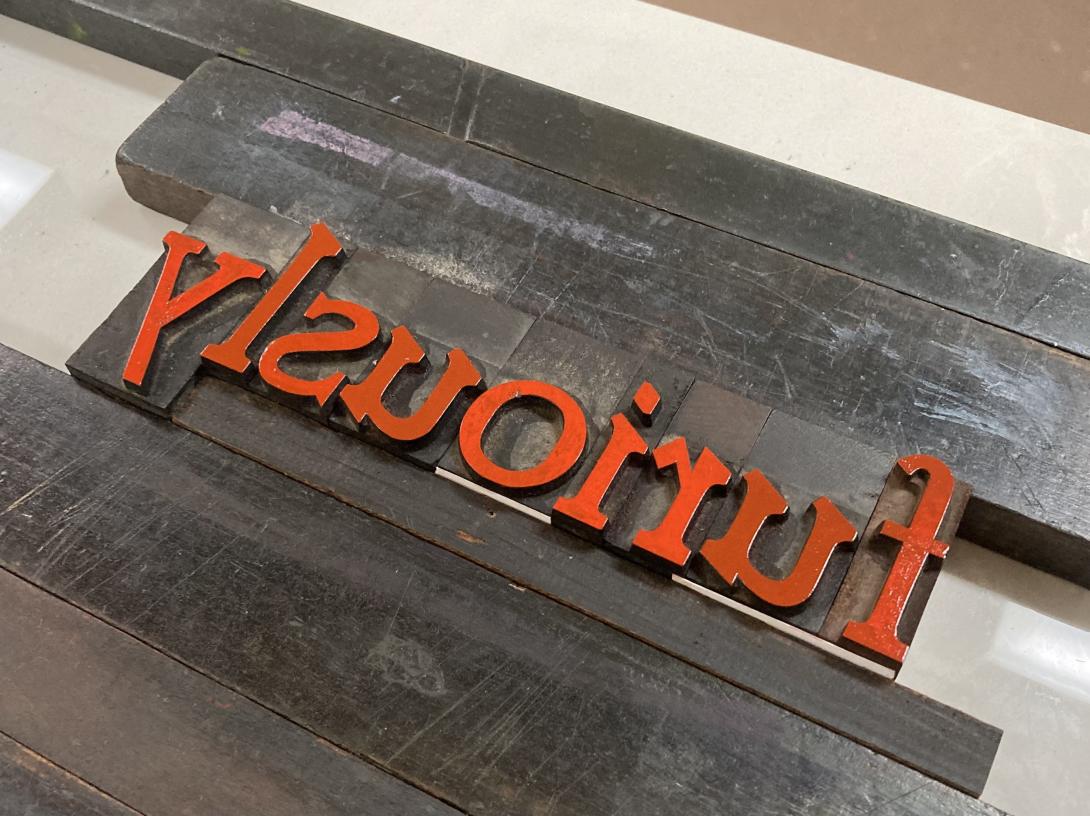 The word "furious", in wooden type, reading right to left, coated with red ink.