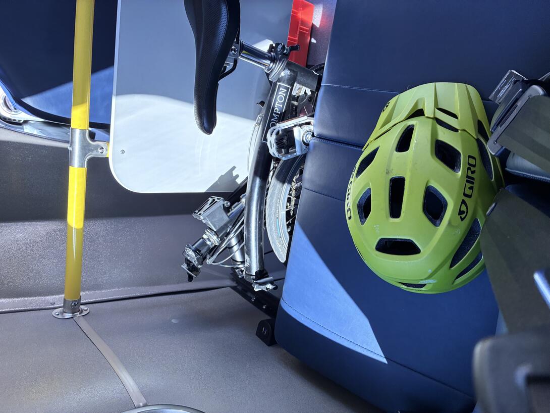 My bicycle tucked in front of a seat on the bus.