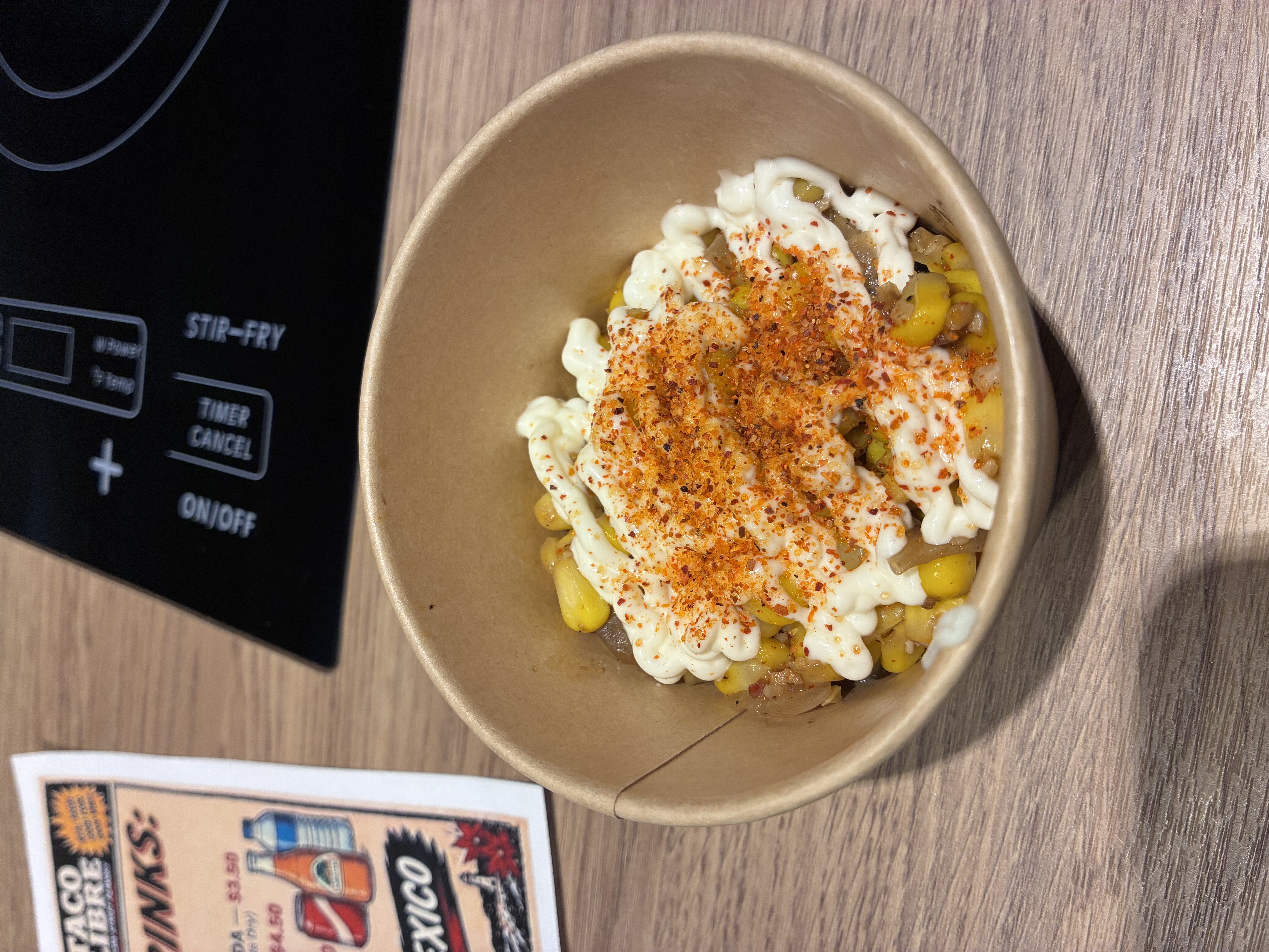 An order of esquites in a brown paper bowl.