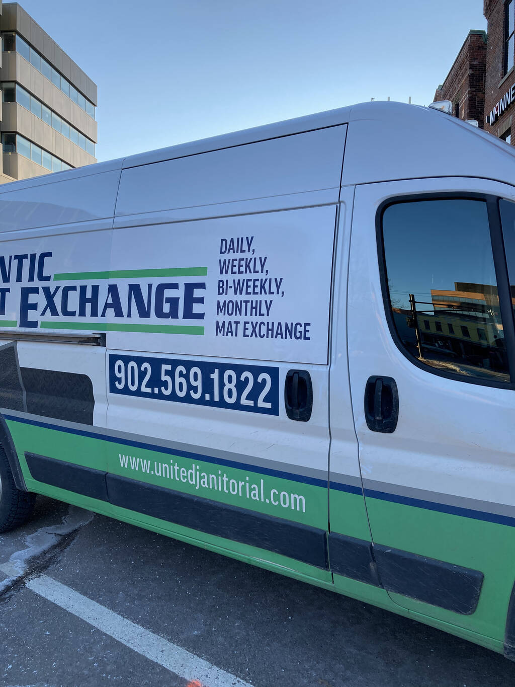 Photo of an Atlantic Mat Exchange van, with "Daily, Weekly, Bi-Weekly, Monthly Mat Exchange" lettered on the side.