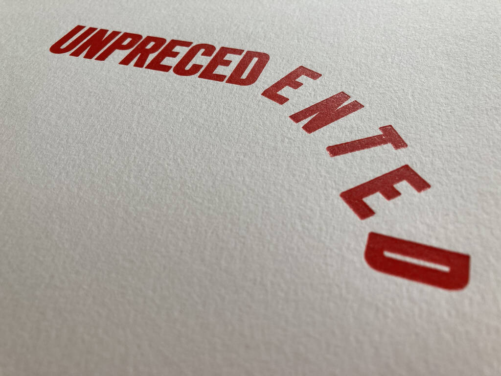 Closeup of UNPRECEDENTED, printed on 140 lb. watercolour paper, with the type creating a deeper impression in the paper.