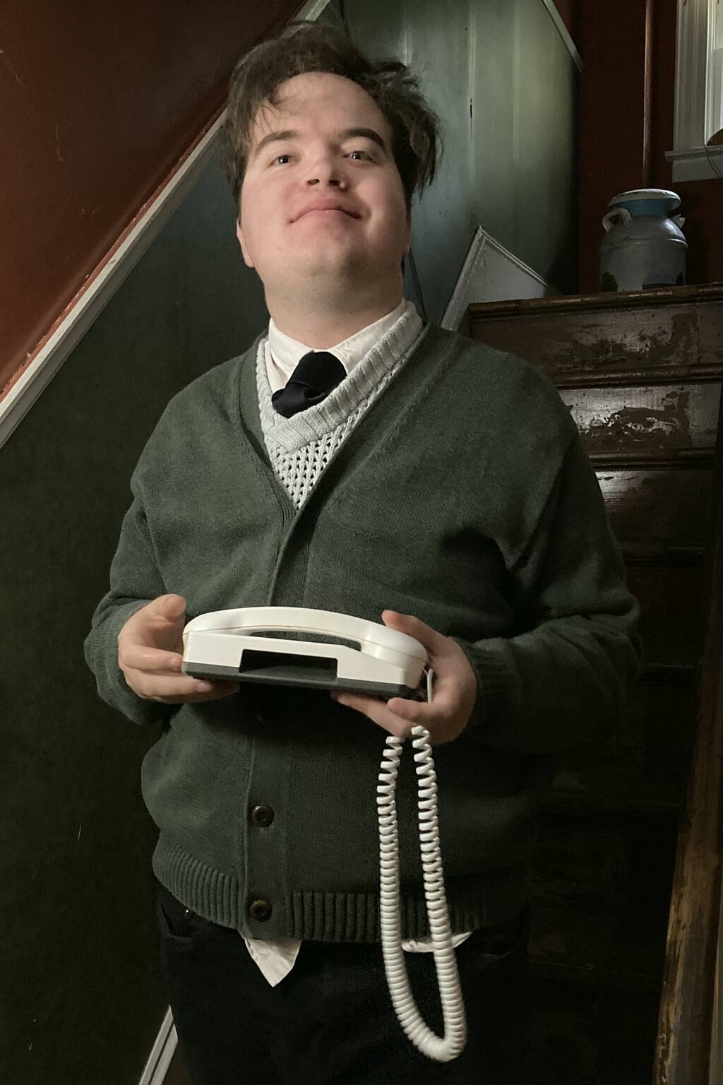 Oliver standing, dressed as Alexander Graham Bell, holding a (modern) telephone.