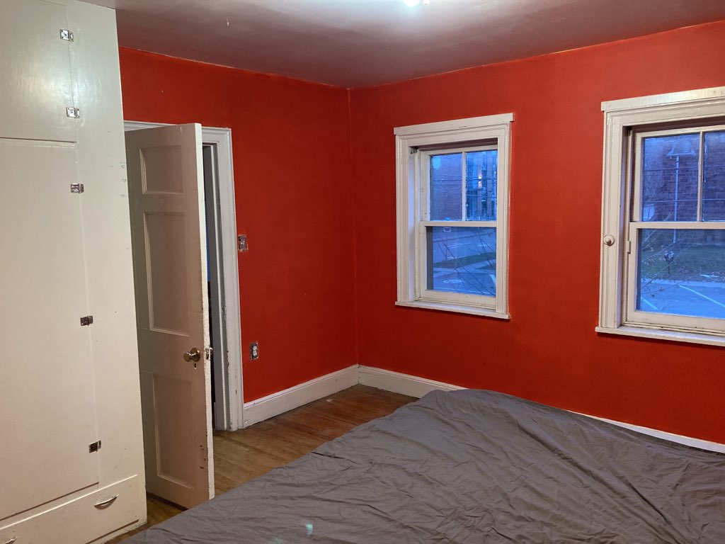 Photo of the upstairs room, walls painted very bright red-orange, with white cabinets, looking toward the street, when it was painted red.