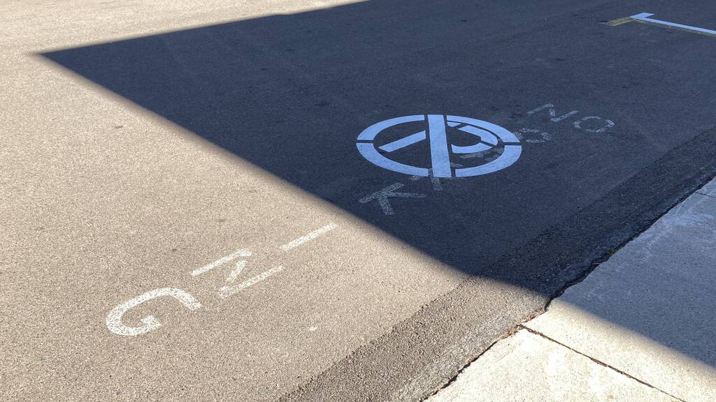 Photo of No Parking zone, showing P with circle and slash painted over the words No Parking from previous years.