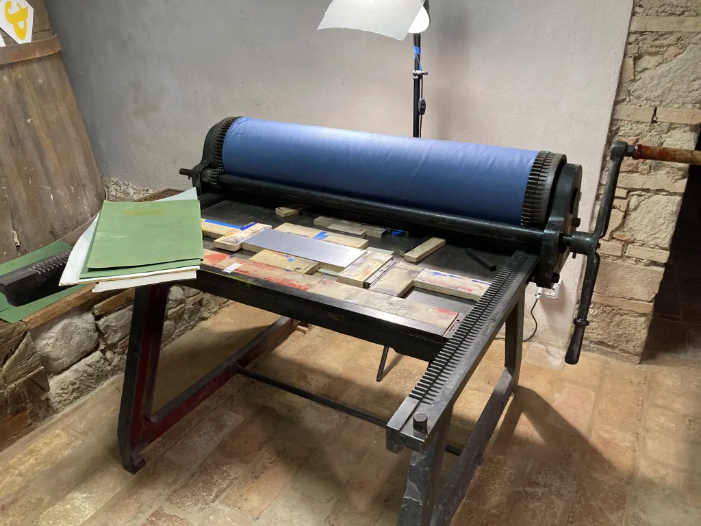A flatbed press with two lino blocks set up to print a solid silver colour.