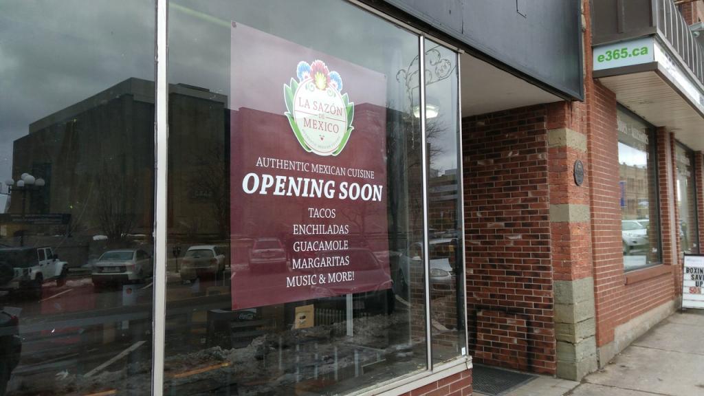Photo of 115 Queen Street storefront, with coming soon sign in the window.