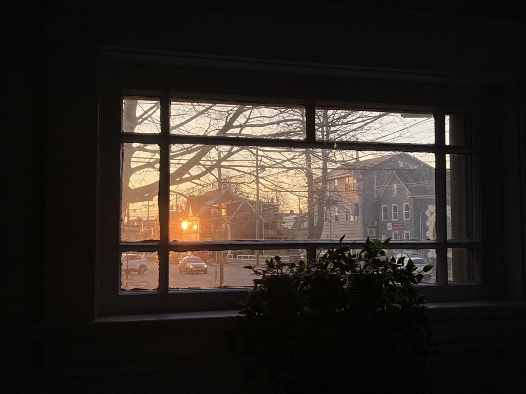 The view of the sunrise reflected in windows down the street, looking out my piano window at 100 Prince Street.