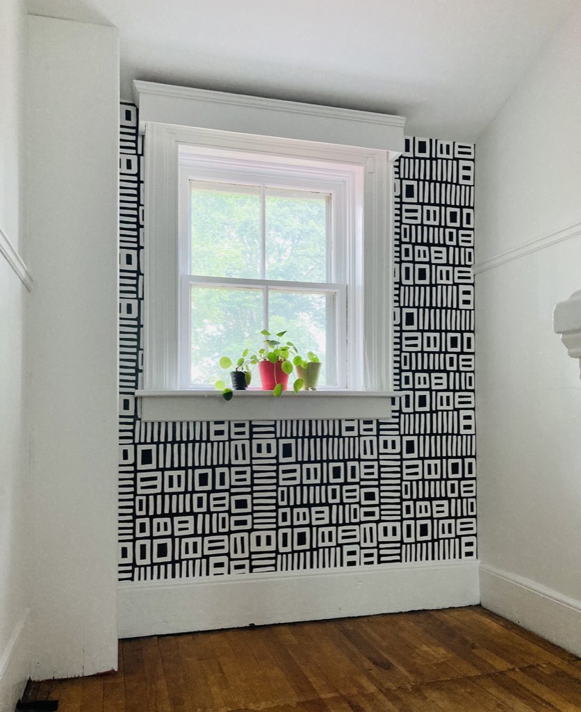 Black and white patterned wallpaper on a back wall with a window.