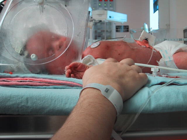 Catherine holding Olivia's hands in the NICU.